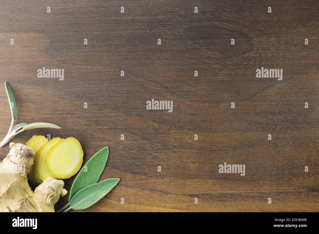 Close-up Holz Nussbaum Schneidebrett mit Ingwerwurzel, Ingwerscheiben und Salbeiblätter. Essen, Trinken, Gewürze und Gesundheitskonzepte Stockfoto