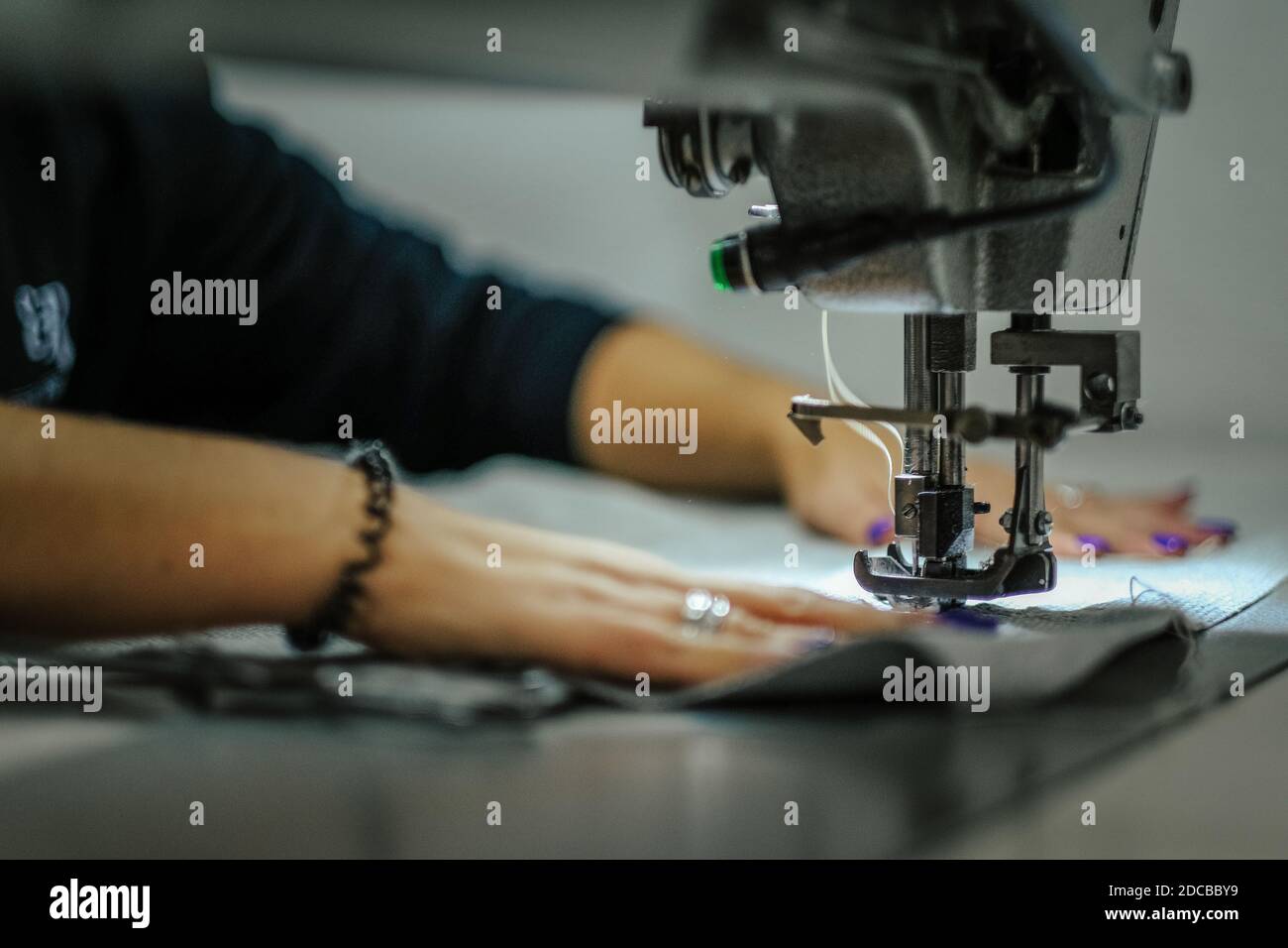 Nahaufnahme einer Frau, die eine Industrienähmaschine betreibt Maschine Stockfoto