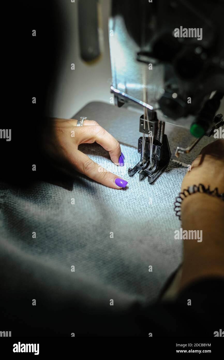 Eine vertikale Nahaufnahme einer Frau, die eine Industrie betreibt Nähmaschine Stockfoto