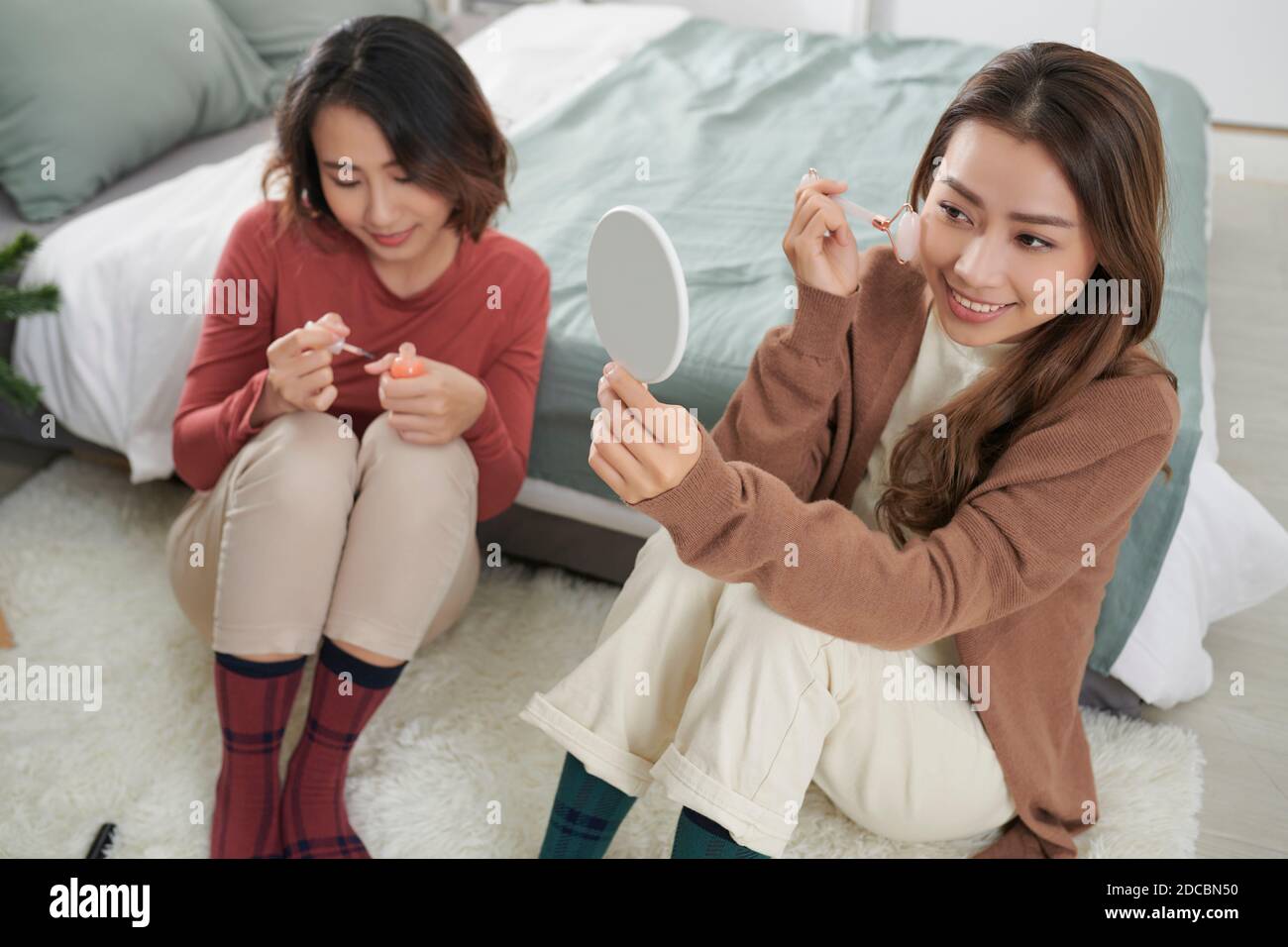 Zwei Frauen zusammen auf einer Pflegebehandlung mit Gesichtsrollen für die Hautstraffung. Stockfoto