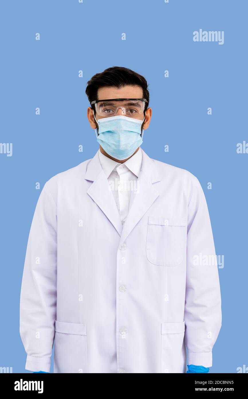 Porträt von zuversichtlich männlichen Nahost-arabischen Forscher Wissenschaftler medizinische Arzt trägt chirurgische Maske und Schutzbrille stehen isoliert auf Stockfoto