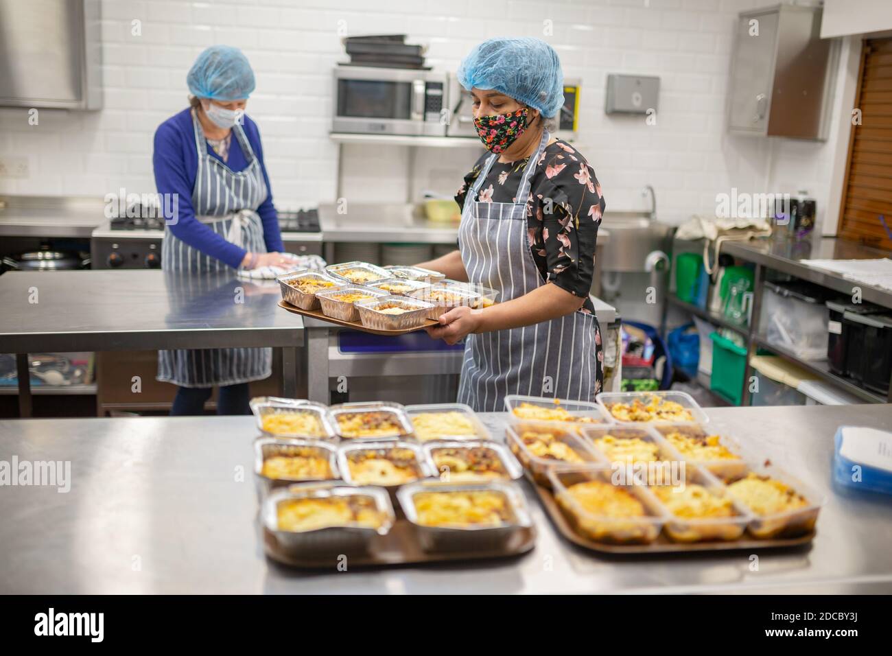 Cradley Heath, West Midlands, Großbritannien. November 2020. Da die Covid-Krise die schwächsten Menschen der Gesellschaft weiterhin betrifft, stellen die Lebensmittelbanken den ärmsten Familien weiterhin dringend benötigte Lebensmittel zur Verfügung. Jeanette Happ und Madhu Frost, Freiwillige in der Holy Trinity Church Foodbank in Cradley Heath, West Midlands, kochen eine Partie Hüttenkuchen, die zum Einfrieren bereit sind. Sie bereiten etwa 30 pro Woche zu geben, um an lokale Familien, die nicht in der Lage sind, ihre eigenen Mahlzeiten zubereiten oder kochen. Kredit: Peter Lopeman/Alamy Live Nachrichten Stockfoto