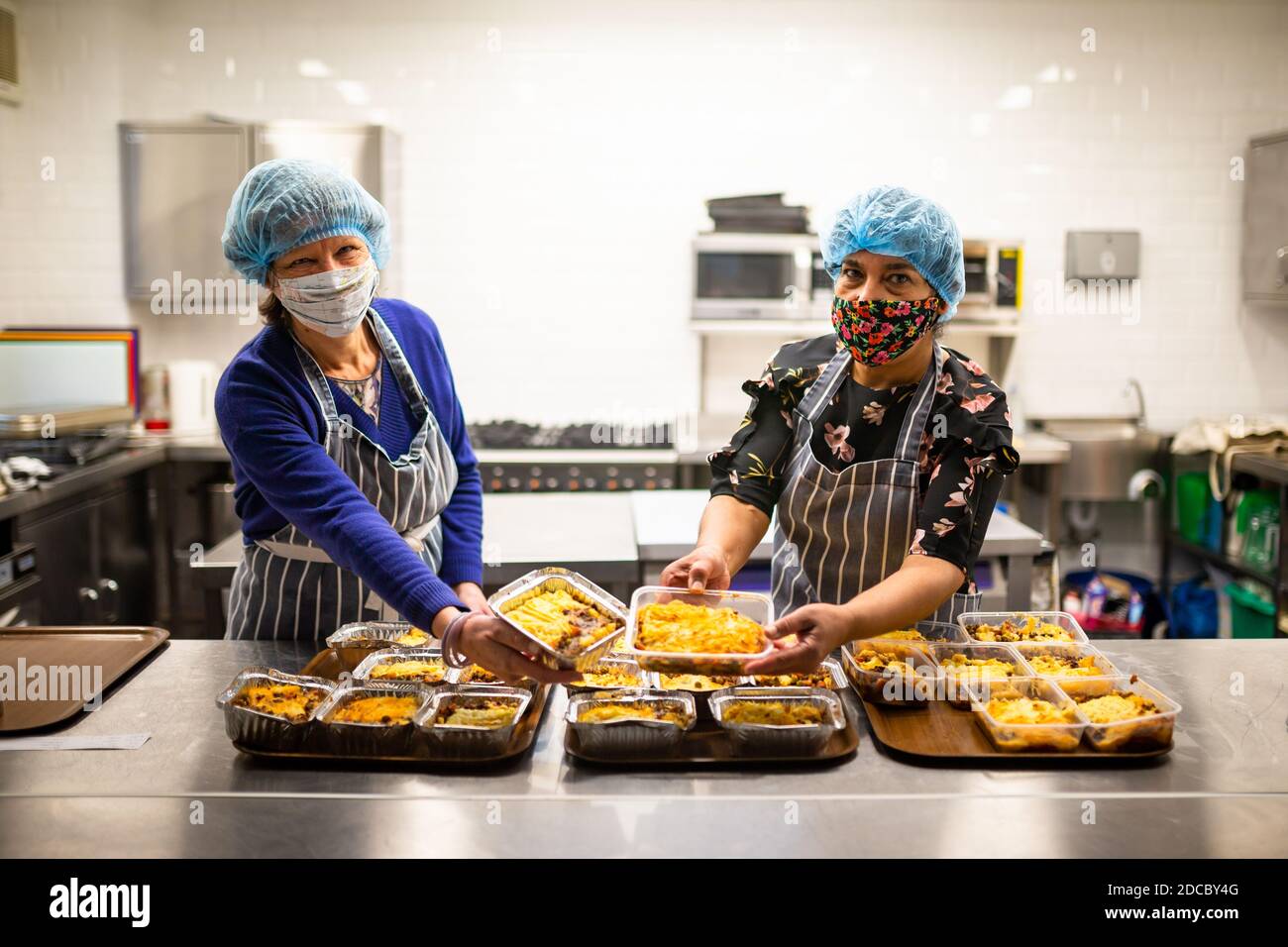 Cradley Heath, West Midlands, Großbritannien. November 2020. Da die Covid-Krise die schwächsten Menschen der Gesellschaft weiterhin betrifft, stellen die Lebensmittelbanken den ärmsten Familien weiterhin dringend benötigte Lebensmittel zur Verfügung. Jeanette Happ und Madhu Frost, Freiwillige in der Holy Trinity Church Foodbank in Cradley Heath, West Midlands, kochen eine Partie Hüttenkuchen, die zum Einfrieren bereit sind. Sie bereiten etwa 30 pro Woche zu geben, um an lokale Familien, die nicht in der Lage sind, ihre eigenen Mahlzeiten zubereiten oder kochen. Kredit: Peter Lopeman/Alamy Live Nachrichten Stockfoto