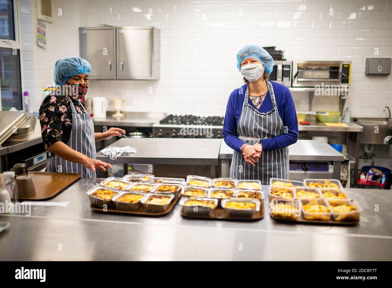 Cradley Heath, West Midlands, Großbritannien. November 2020. Da die Covid-Krise die schwächsten Menschen der Gesellschaft weiterhin betrifft, stellen die Lebensmittelbanken den ärmsten Familien weiterhin dringend benötigte Lebensmittel zur Verfügung. Jeanette Happ und Madhu Frost, Freiwillige in der Holy Trinity Church Foodbank in Cradley Heath, West Midlands, kochen eine Partie Hüttenkuchen, die zum Einfrieren bereit sind. Sie bereiten etwa 30 pro Woche zu geben, um an lokale Familien, die nicht in der Lage sind, ihre eigenen Mahlzeiten zubereiten oder kochen. Kredit: Peter Lopeman/Alamy Live Nachrichten Stockfoto