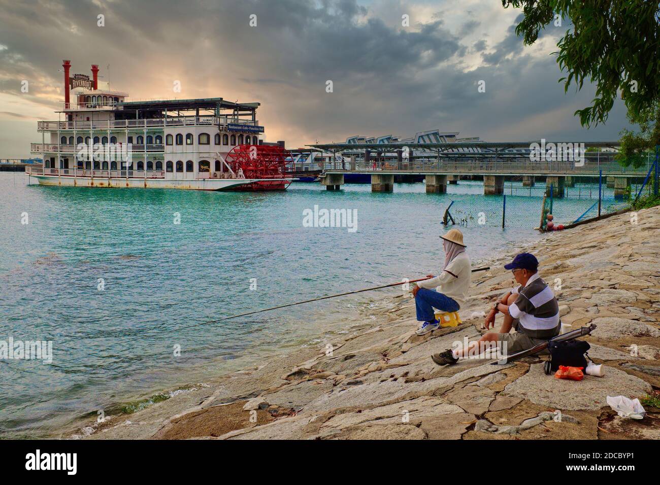 Zwei Angler sitzen in der Nähe des Marina South Pier, Singapur, im b/g Stewords Riverboat (seit 2019 nicht mehr verfügbar), einst in einem Restaurant und einem Biergarten Stockfoto