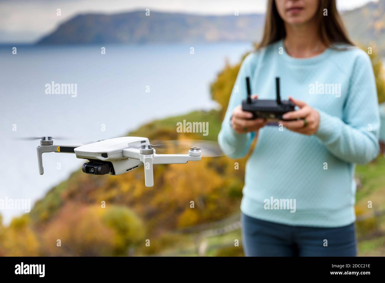 Verschwommene Figur des Mädchens steuert eine Drohne auf Herbst verschwommen Hintergrund. Weichfokus-Konsept Stockfoto