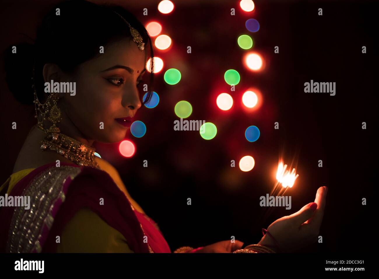 Nahaufnahme Porträt der jungen und schönen indischen Bengali Frau in indischen traditionellen Kleid feiert Diwali mit Räucherstäbchen in dunklem Hintergrund. Stockfoto