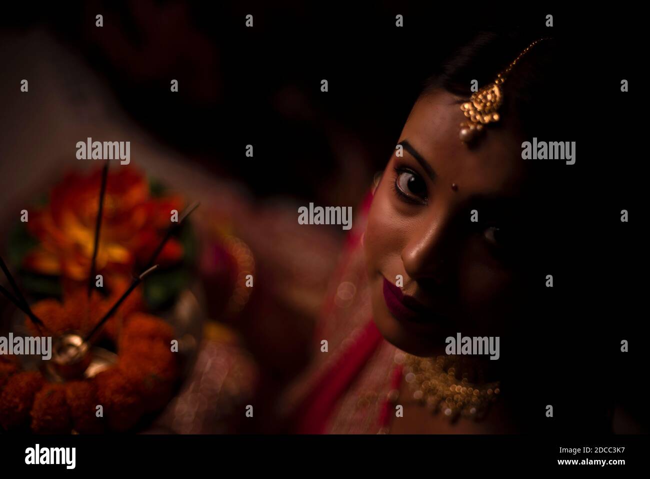Nahaufnahme Porträt von jungen und schönen indischen Bengali Frau in indischen traditionellen Kleid feiert Diwali mit Blumen in dunklem Hintergrund. Stockfoto