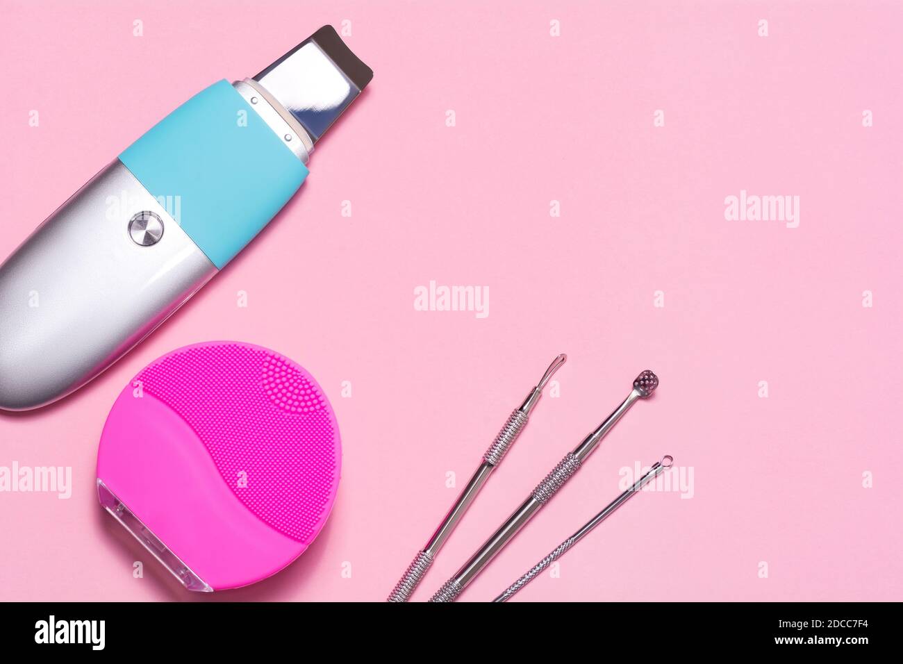 Gesichtsreinigungswerkzeuge auf einem rosa Hintergrund. Ultraschallgeräte, Silikonbürste und uno-Löffel Stockfoto