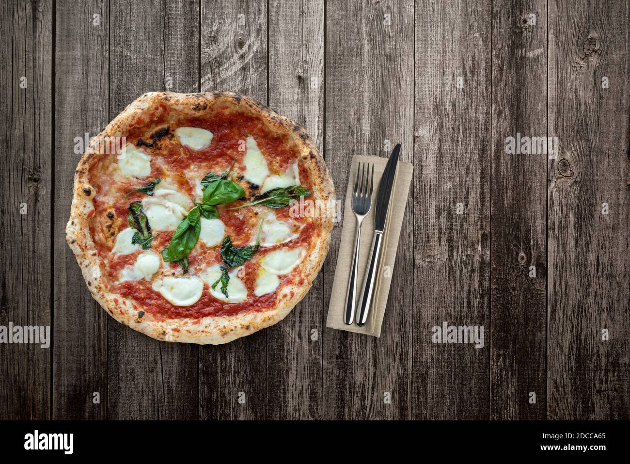 Blick von oben auf Pizza auf Holztisch mit Besteck Stockfoto