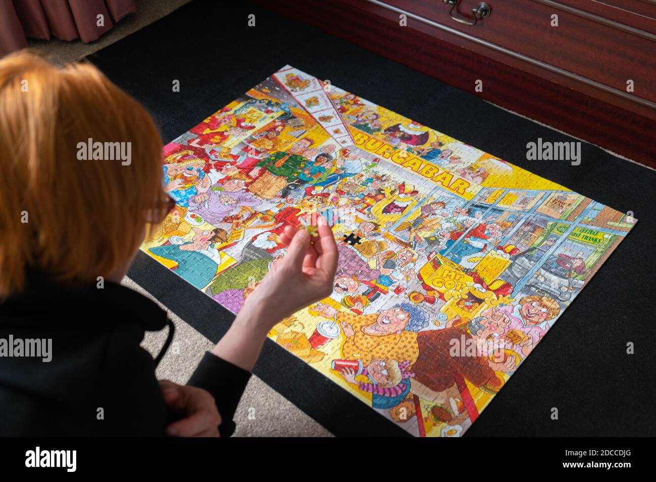 Eine Frau mit roten Haaren, die ein buntes Puzzle vervollständigt Stockfoto