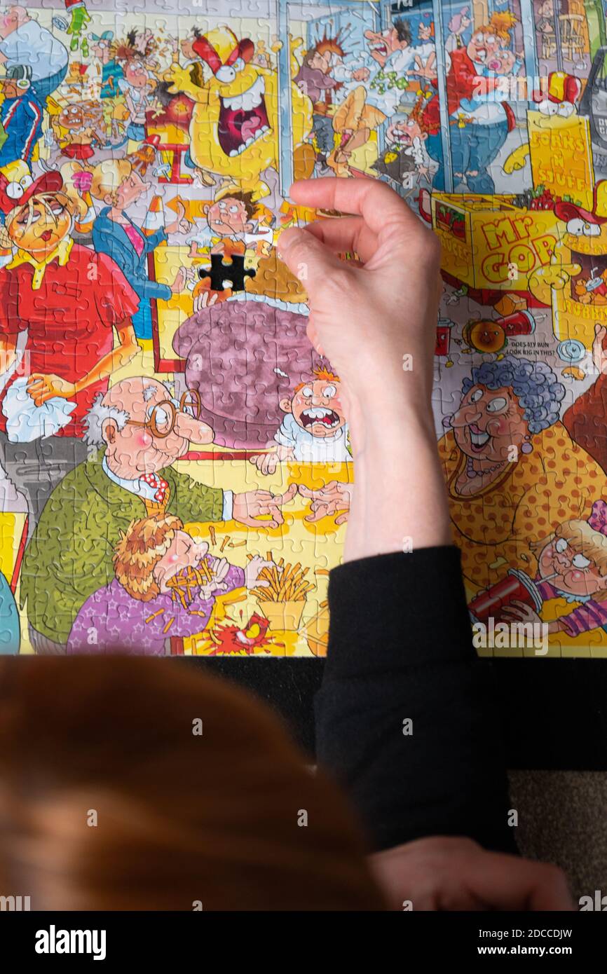 Eine Frau mit roten Haaren im Begriff, eine bunte abzuschließen puzzle Stockfoto