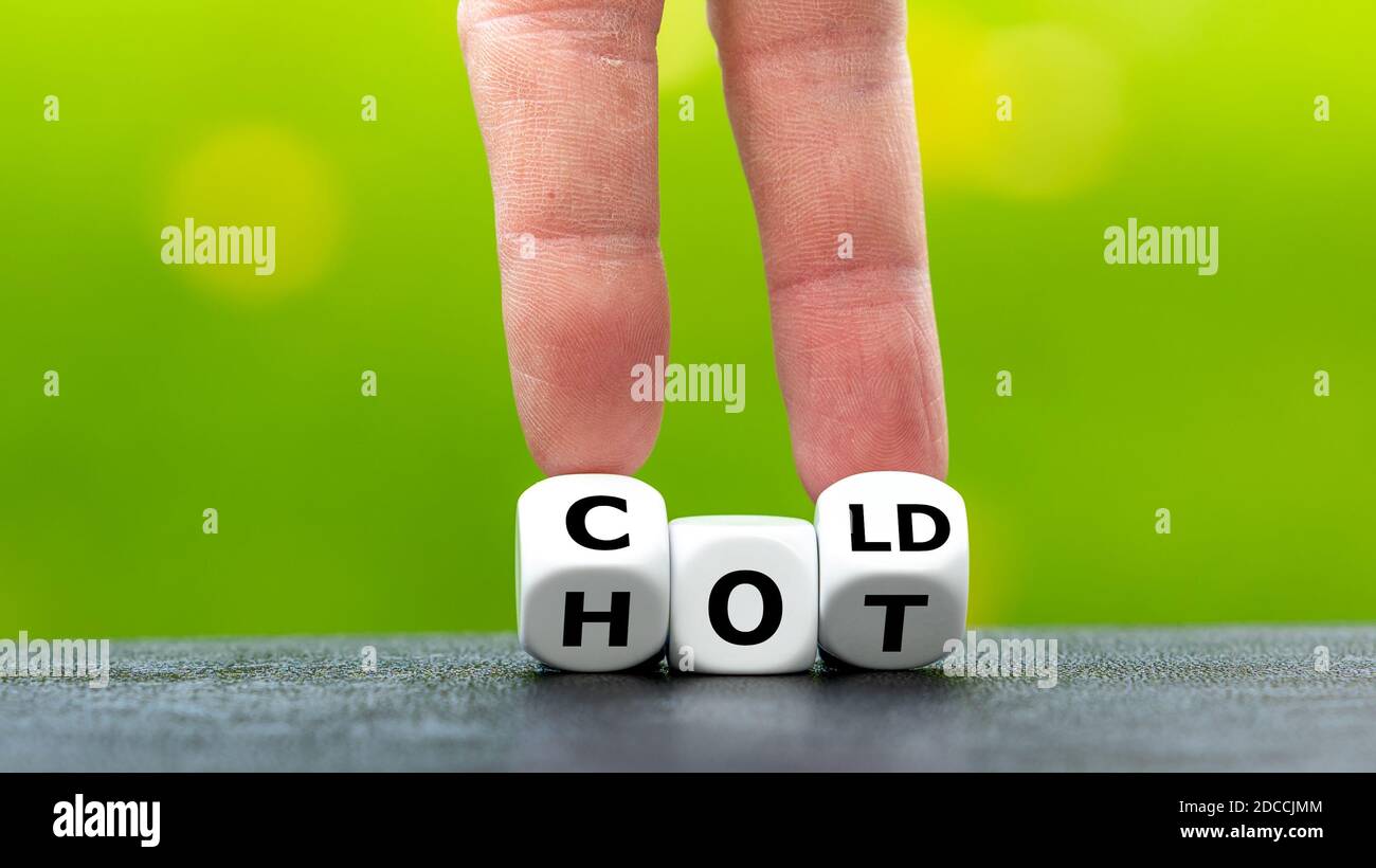 Hand dreht Würfel und ändert das Wort "heiß" zu "kalt". Stockfoto