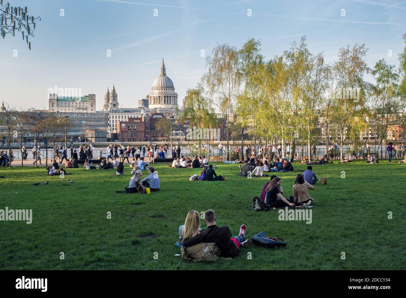 Die Menschen genießen einen heißen Tag auf dem Rasen vor der Tate Modern mit Blick auf die Themse, die St. Paul's Cathedral, London, Großbritannien Stockfoto