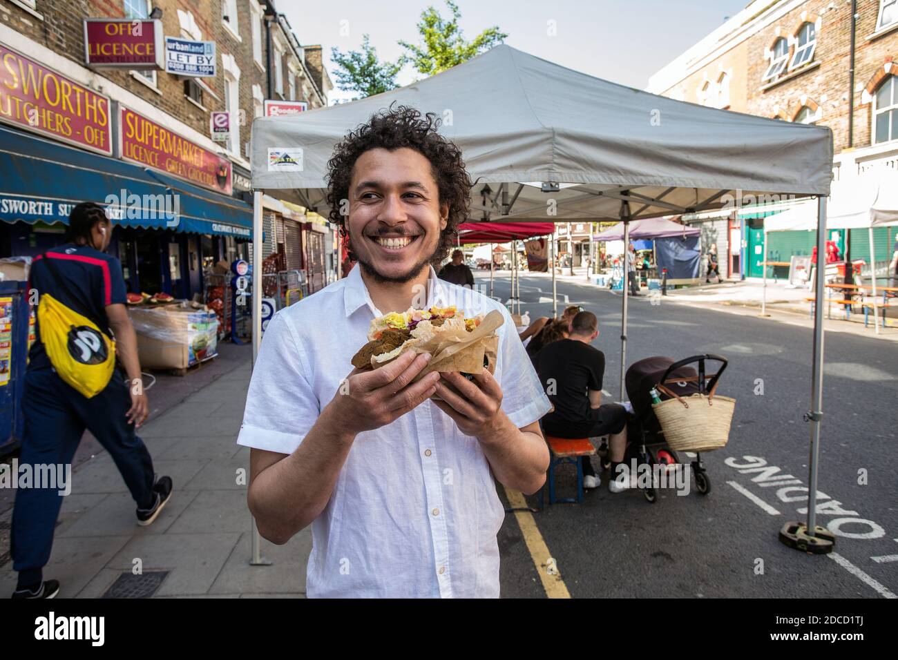 Großbritannien / England /London / Hackney/ junger Mann isst Street Food auf dem Chatsworth Road Market. Stockfoto
