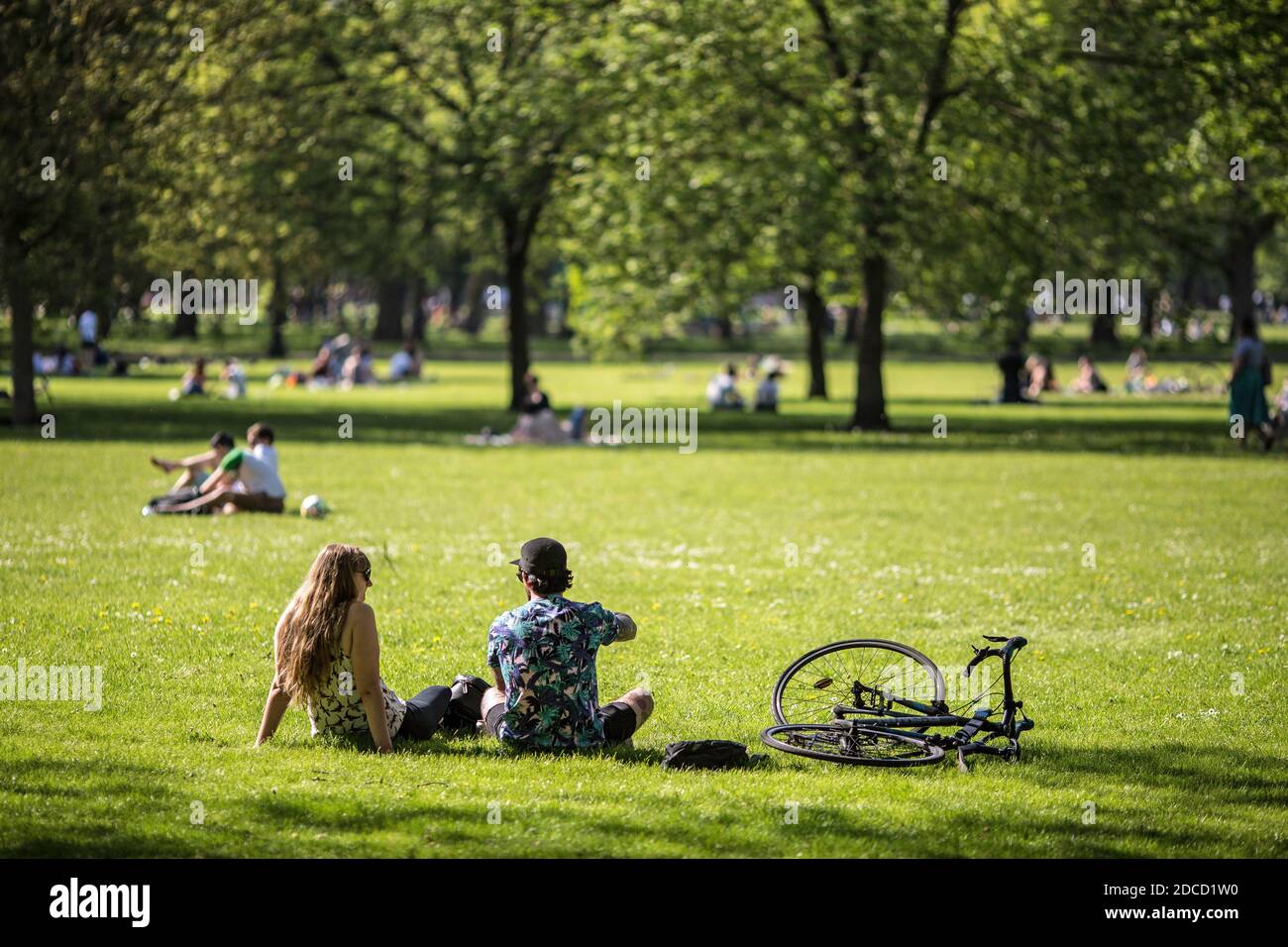 Menschen sitzen auf dem Rasen im Victoria Park, Tower Hamlets in East London, Großbritannien. Stockfoto