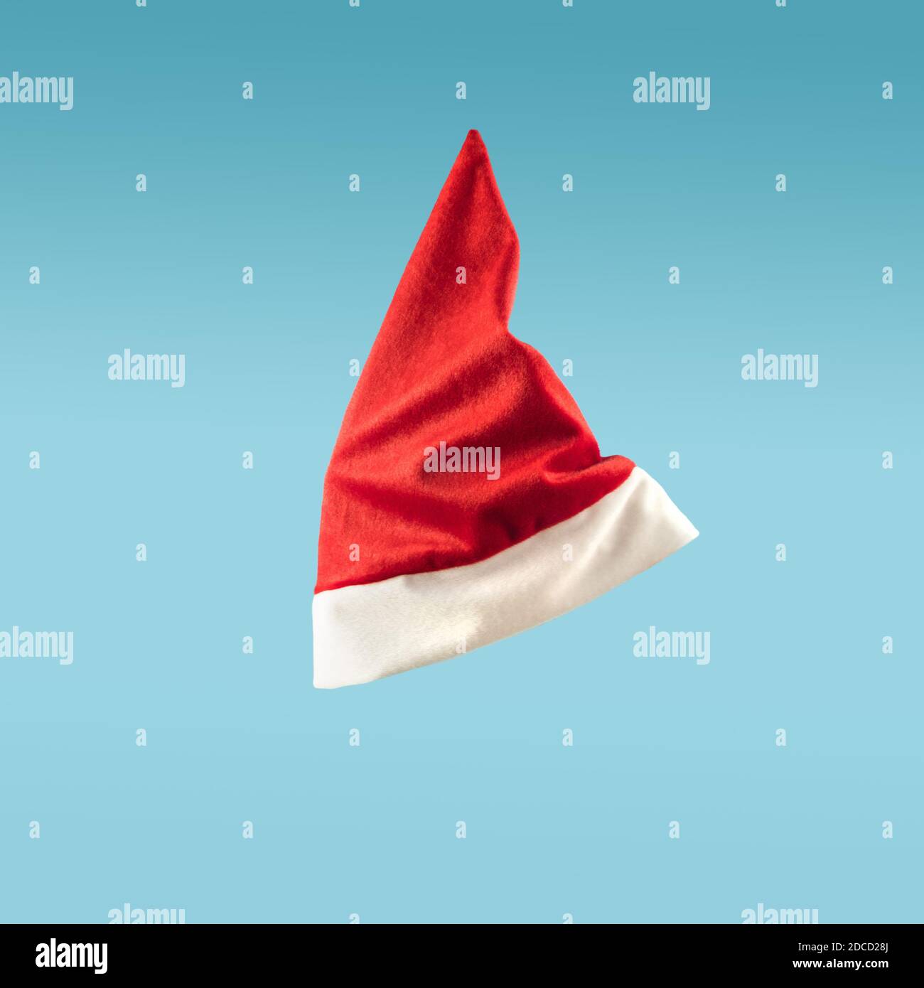 Santa Claus Hut Levitation auf blauem Hintergrund. Minimales Weihnachtskonzept. Fliegende Kappe in der Luft Stockfoto