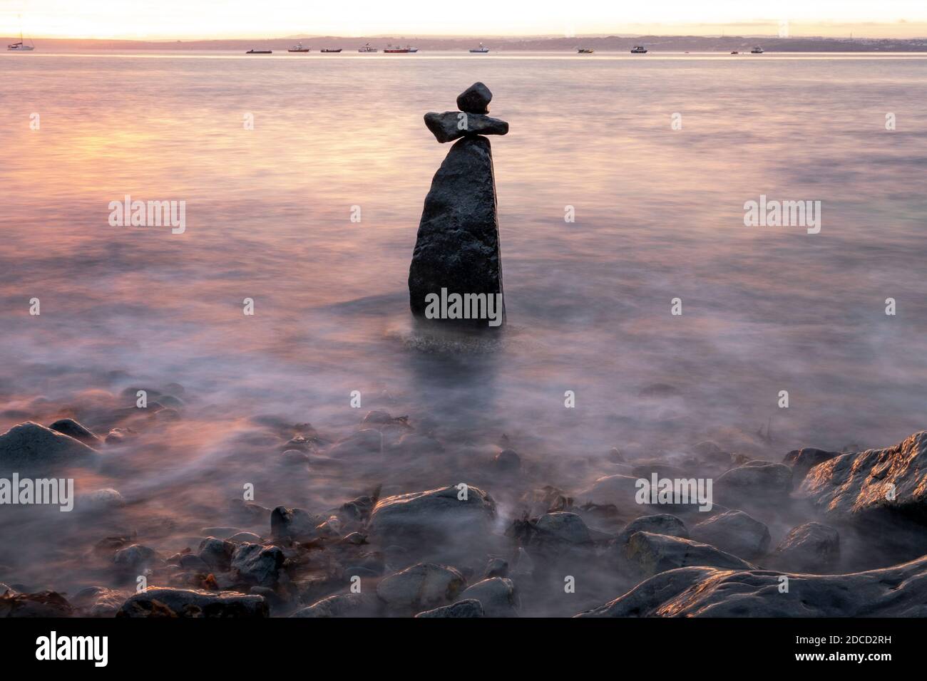 Balancierende Felsen in Form eines Kreuzes im Meer, Boote in St. Ives Bucht dahinter festgemacht Stockfoto