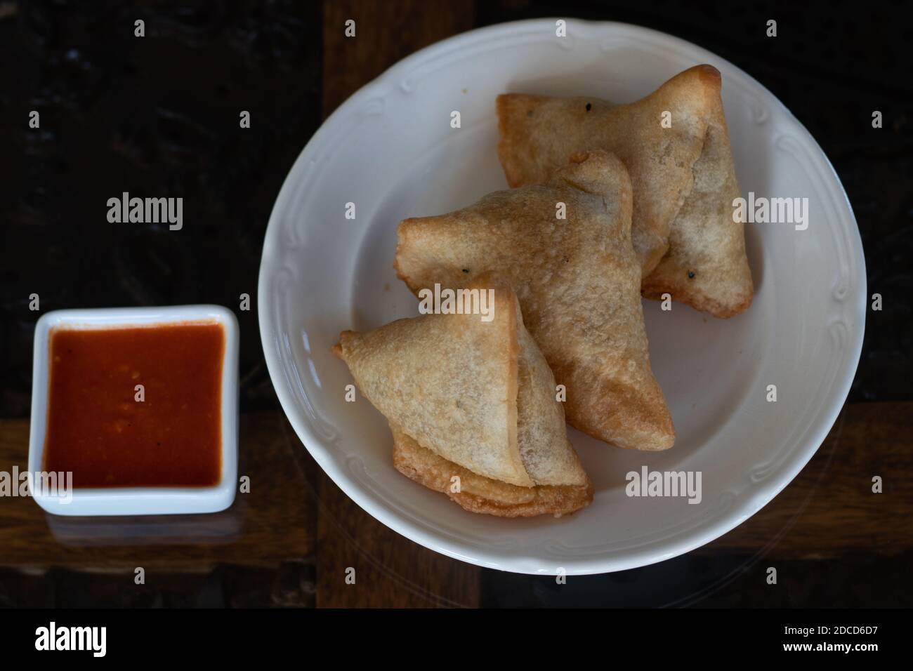 Samosas auf einem weißen Teller mit dippender würziger roter Sauce Stockfoto