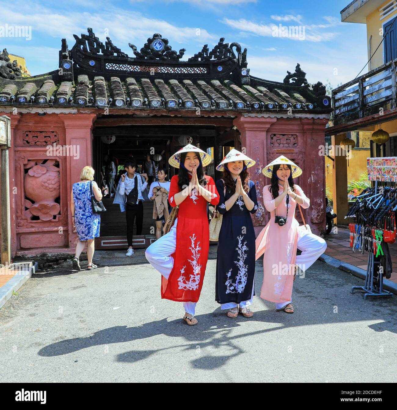 Drei vietnamesische junge Damen in traditioneller Kleidung, die Ao dai, posiert für ein Foto an der japanischen überdachten Brücke, Hoi an, Vietnam, Asien Stockfoto