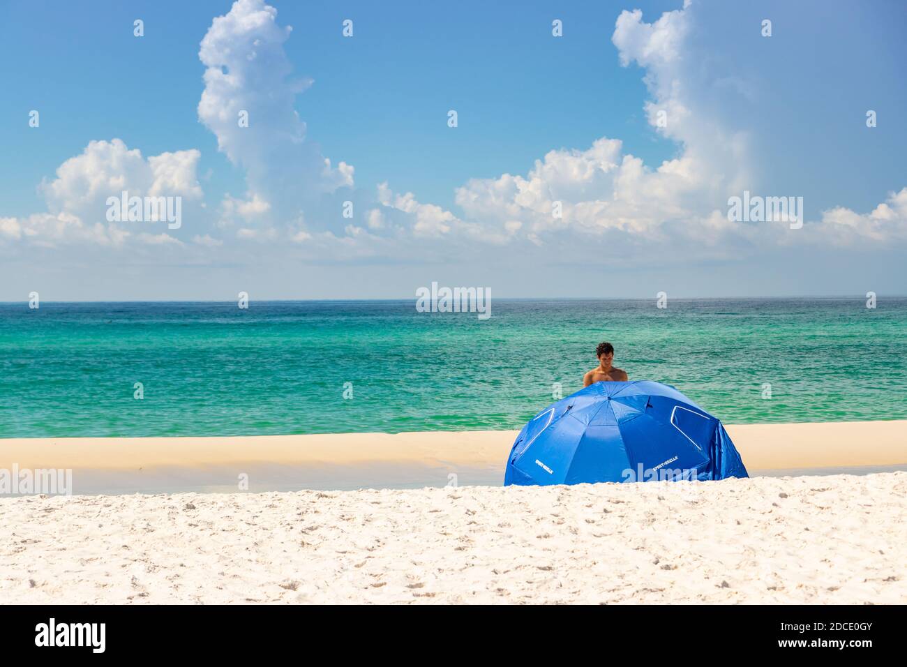 Junge gebräunte Bräune im grünen Meer mit Sonnenschirm Strand am Biloxi Mississippi USA Stockfoto
