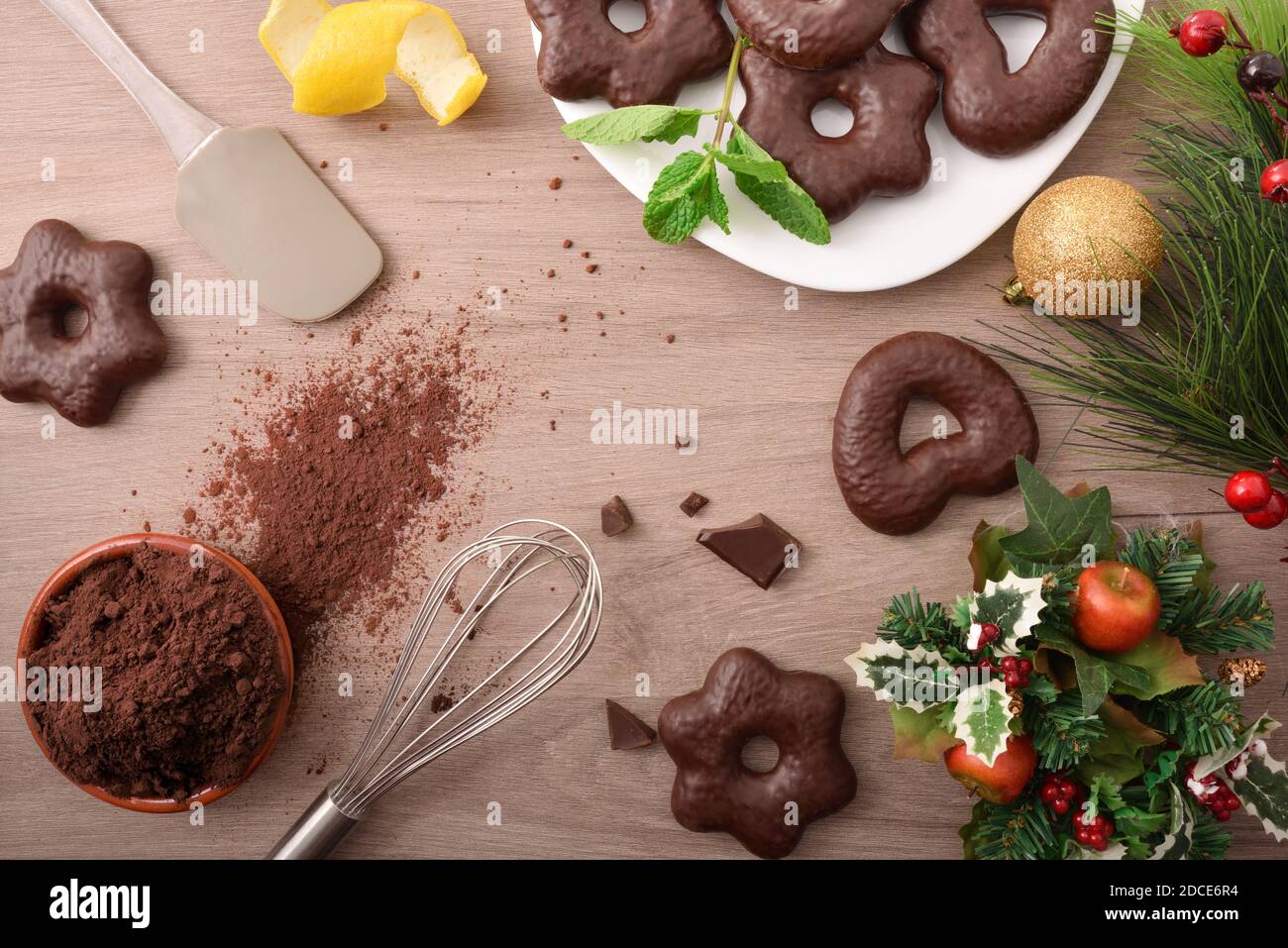 Herstellung von mit Schokolade überzogenen Keksen auf einer Holzbank mit Weihnachtsdekorationen. Draufsicht. Horizontale Zusammensetzung. Stockfoto