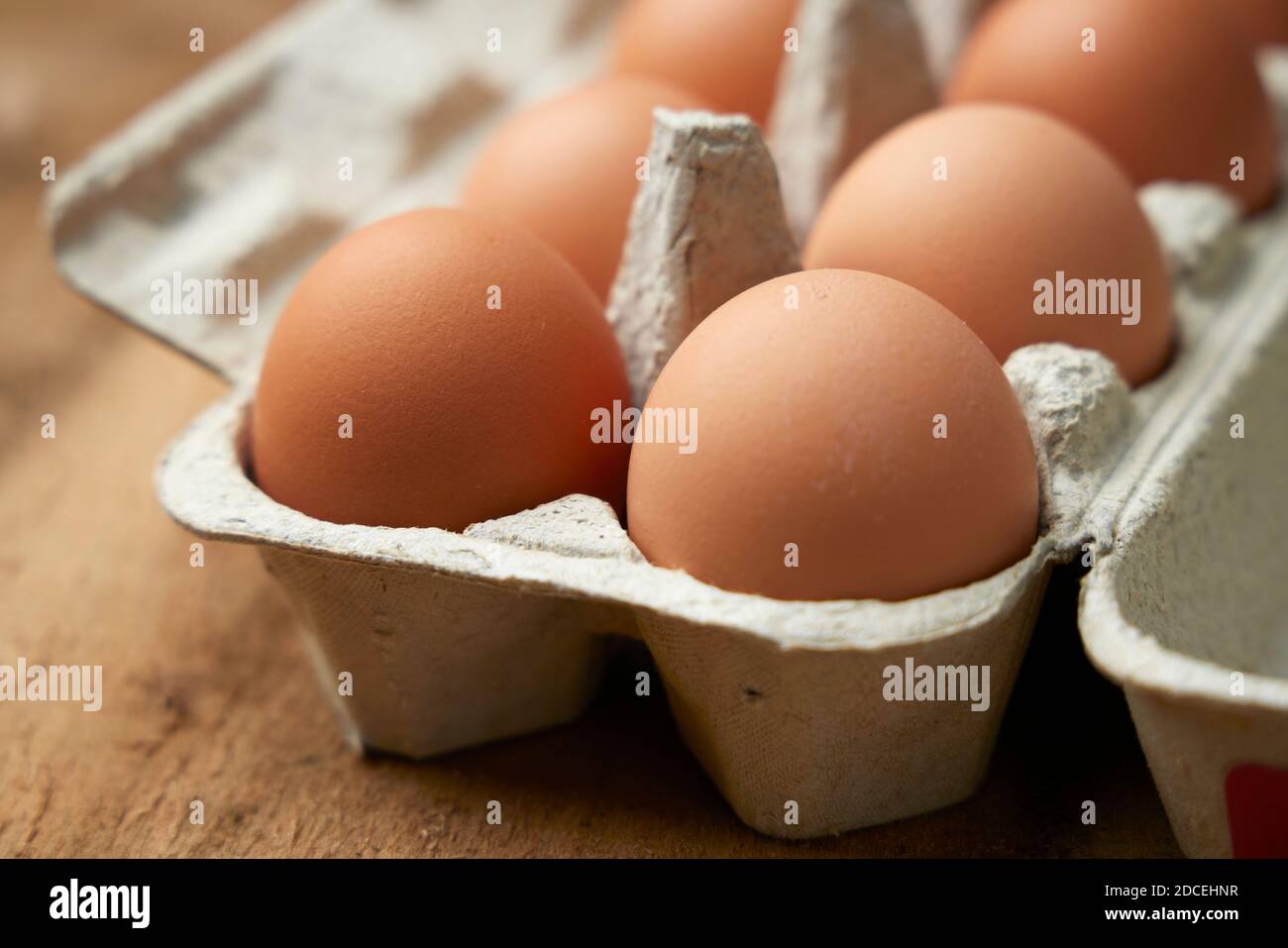 Eier in einem Karton auf verwittertem Holzhintergrund braun anbraten Stockfoto