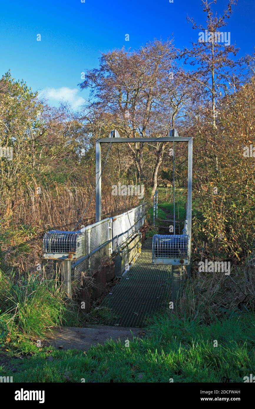 Eine Zugbrücke aus Metall, die es einem Fußweg ermöglicht, einen kleinen Deich am Fluss Ant auf den Norfolk Broads in Ludham, Norfolk, England, Vereinigtes Königreich zu überqueren. Stockfoto