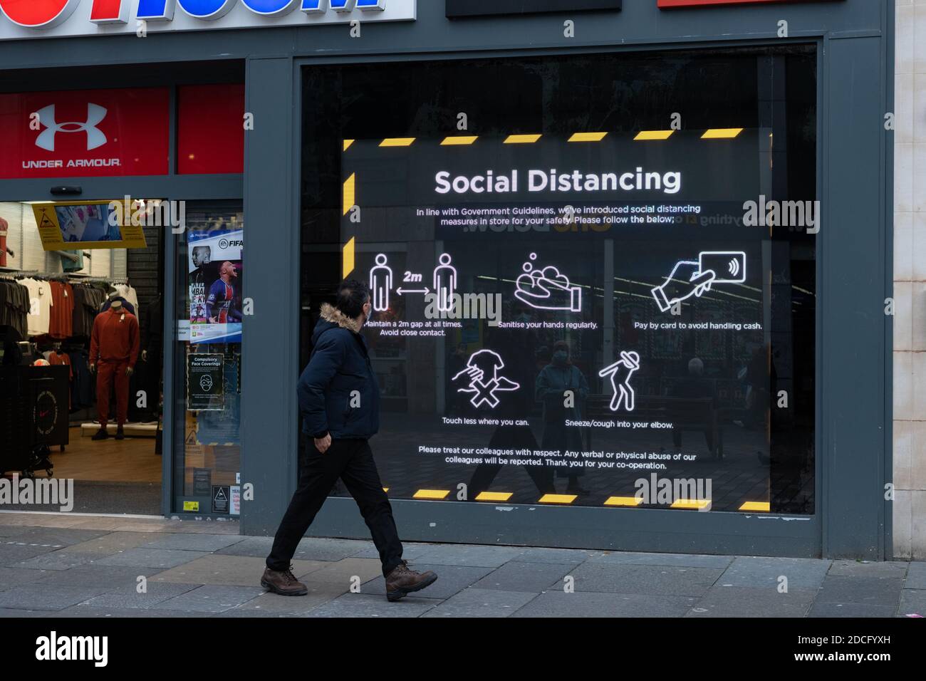 Ein Mitglied der Öffentlichkeit geht während der Coronavirus-Pandemie an einem sozialen Distanzierungsschild in Glasgow, Schottland, Großbritannien vorbei Stockfoto