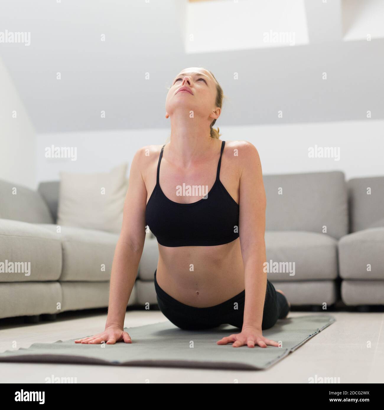 Schöne blonde Frau tun zu Hause Training drinnen. Frau praktiziert Yoga zu Hause. Fit Mädchen mit Workout-Tutorials für einen gesunden aktiven Lebensstil. Frau Stockfoto