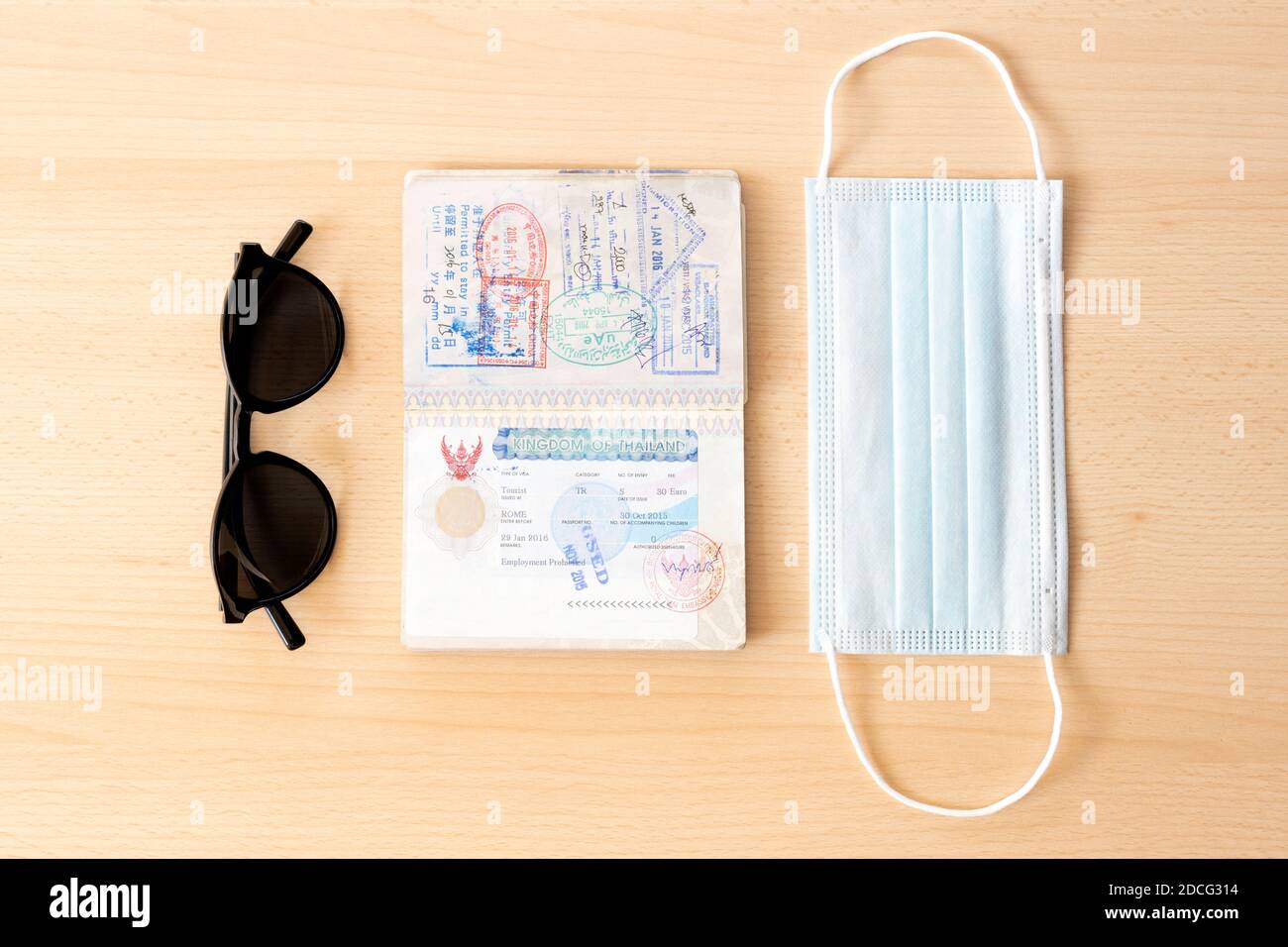 Sicheres Reisekonzept, Gesichtsmaske, Reisepass und Sonnenbrille sind auf einem Holztisch angeordnet. Stockfoto