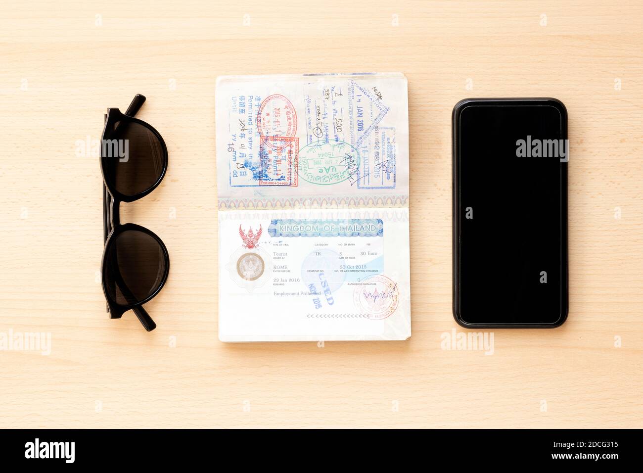 Reisekonzept, Reisepass, Sonnenbrille und Smartphone sind auf einem Holztisch angeordnet. Stockfoto