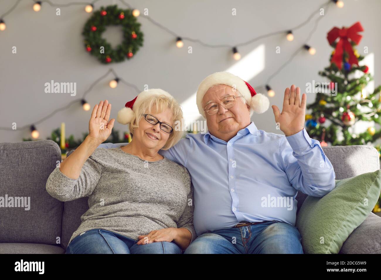 Ältere Frau und Mann in Weihnachtsmützen winken vor der Webcam Gruß Familie. Stockfoto