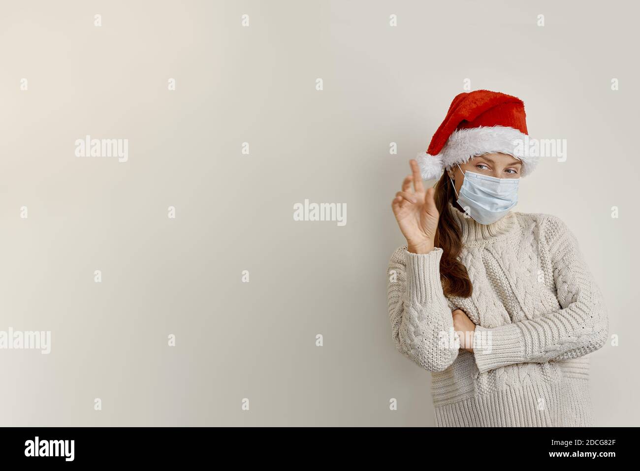 Frau trägt Schutzmaske zeigt mit Hand und Finger nach oben Zur Seite Stockfoto