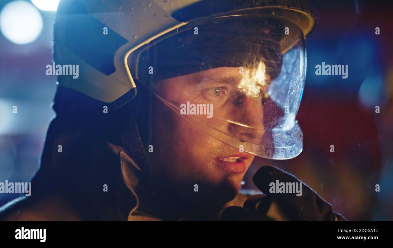 Porträt des Feuerwehrmunes in voller Uniform bei nächtlichem Regen. Stockfoto