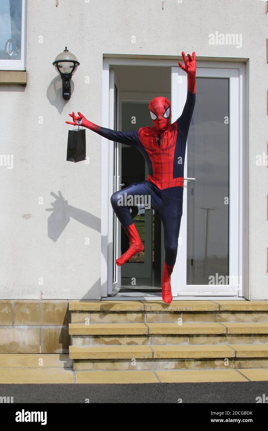 Kostüm Fancy Kleid Charaktere, Mann als Spiderman springt von einer Tür gekleidet Stockfoto