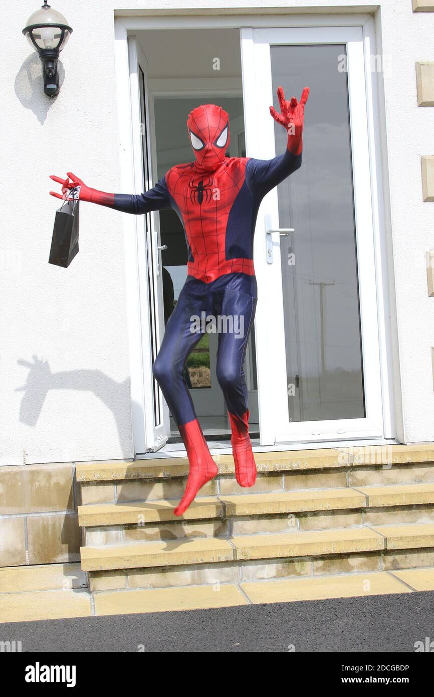 Kostüm Fancy Kleid Charaktere, Mann als Spiderman springt von einer Tür gekleidet Stockfoto