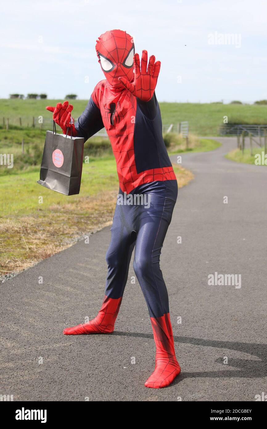 Kostüm Fancy Kleid Charaktere, Mann als Spiderman springt von einer Tür gekleidet Stockfoto