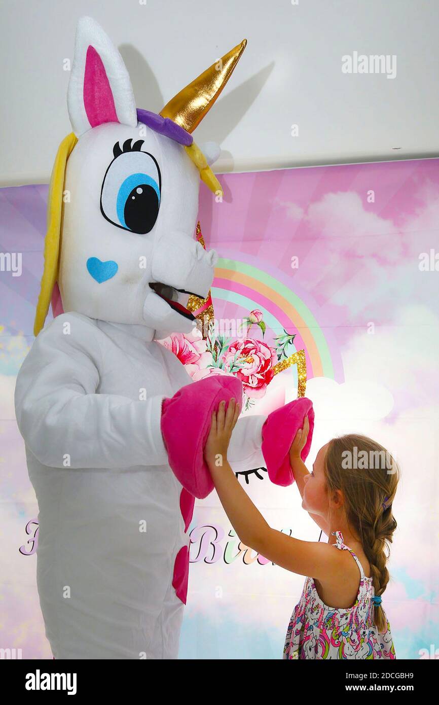 Kostüm fancy Kleid Zeichen. Ein kleines Mädchen High Fives ein Einhorn Stockfoto