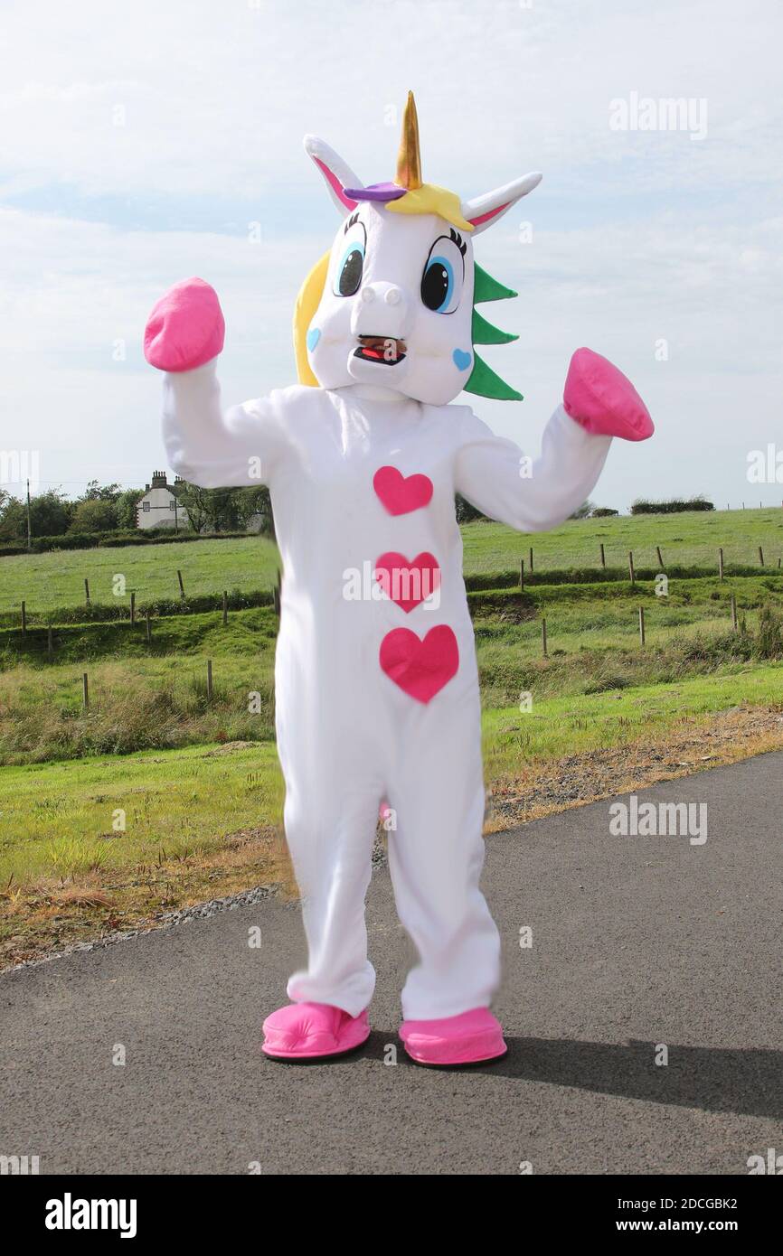 Kostüm fancy Kleid Zeichen. Frau im riesigen rosa-weißen Einhorn Kostüm klopft an eine Haustüre Stockfoto