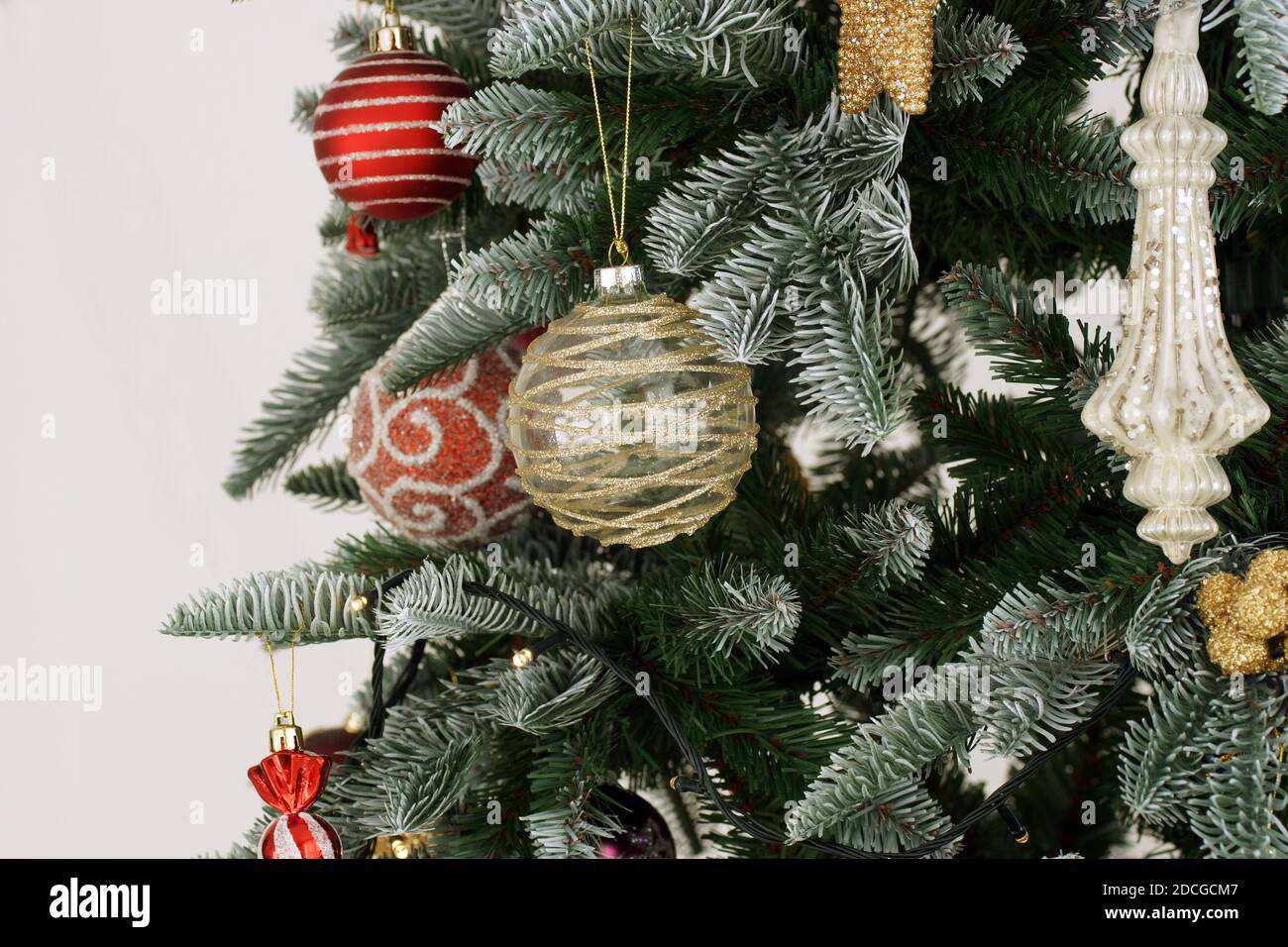 Weihnachtsschmuck auf einem Baum im Haus. Rote und goldene Weihnachtsdekorationen hängen vom Baum. Stockfoto