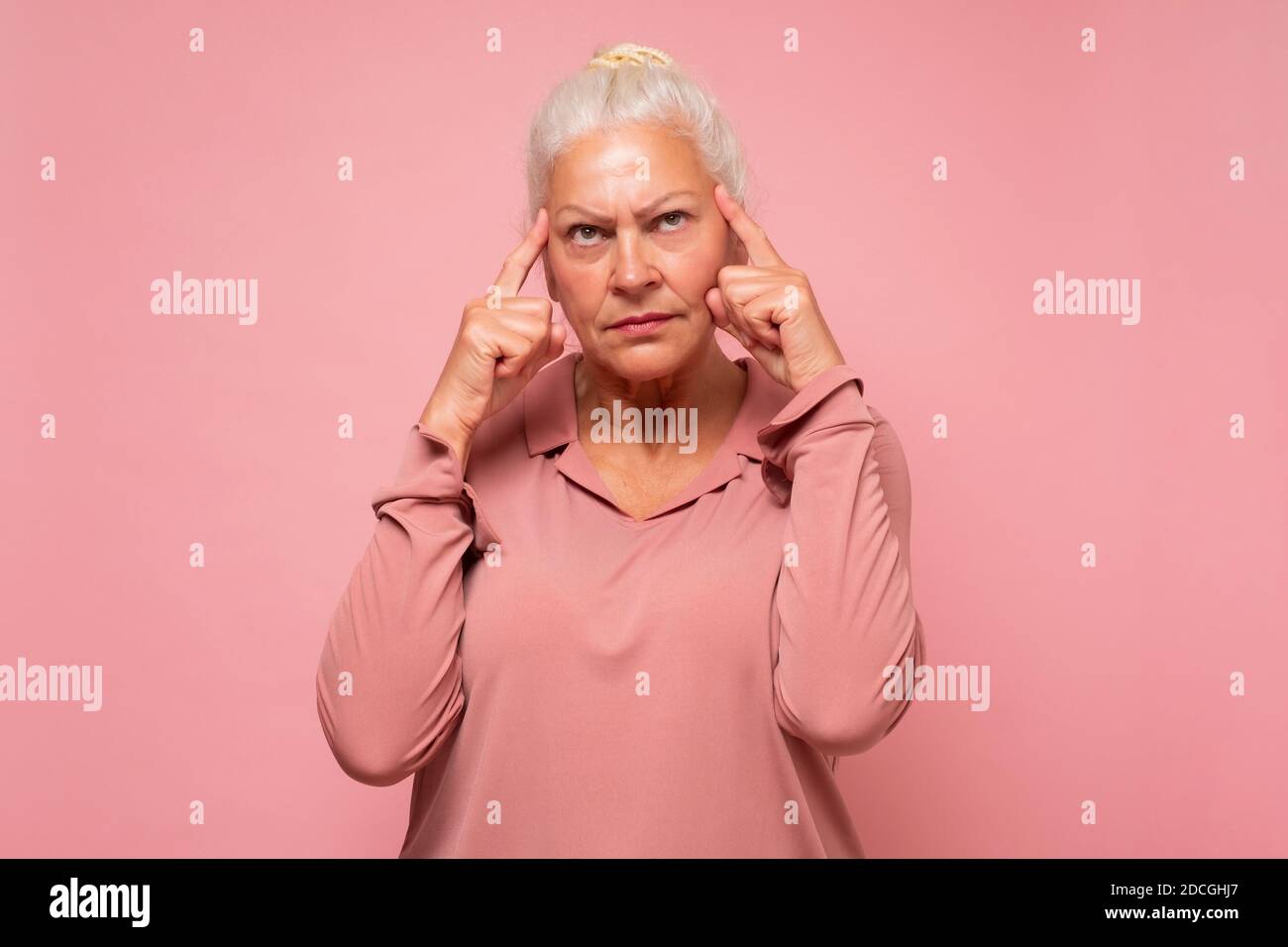 Ältere kaukasische Frau, die Zweifel hat und verwirrt ist, über eine Idee nachdenkt oder sich um ihre Familie sorgt. Studio auf rosa Wand aufgenommen. Stockfoto