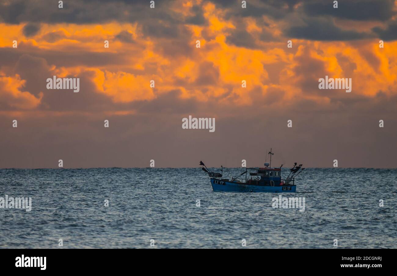 Kleines Fischerboot für eine Person auf See am Abend, wenn die Sonne untergeht, vor der Südküste von West Sussex, England, Großbritannien. Stockfoto