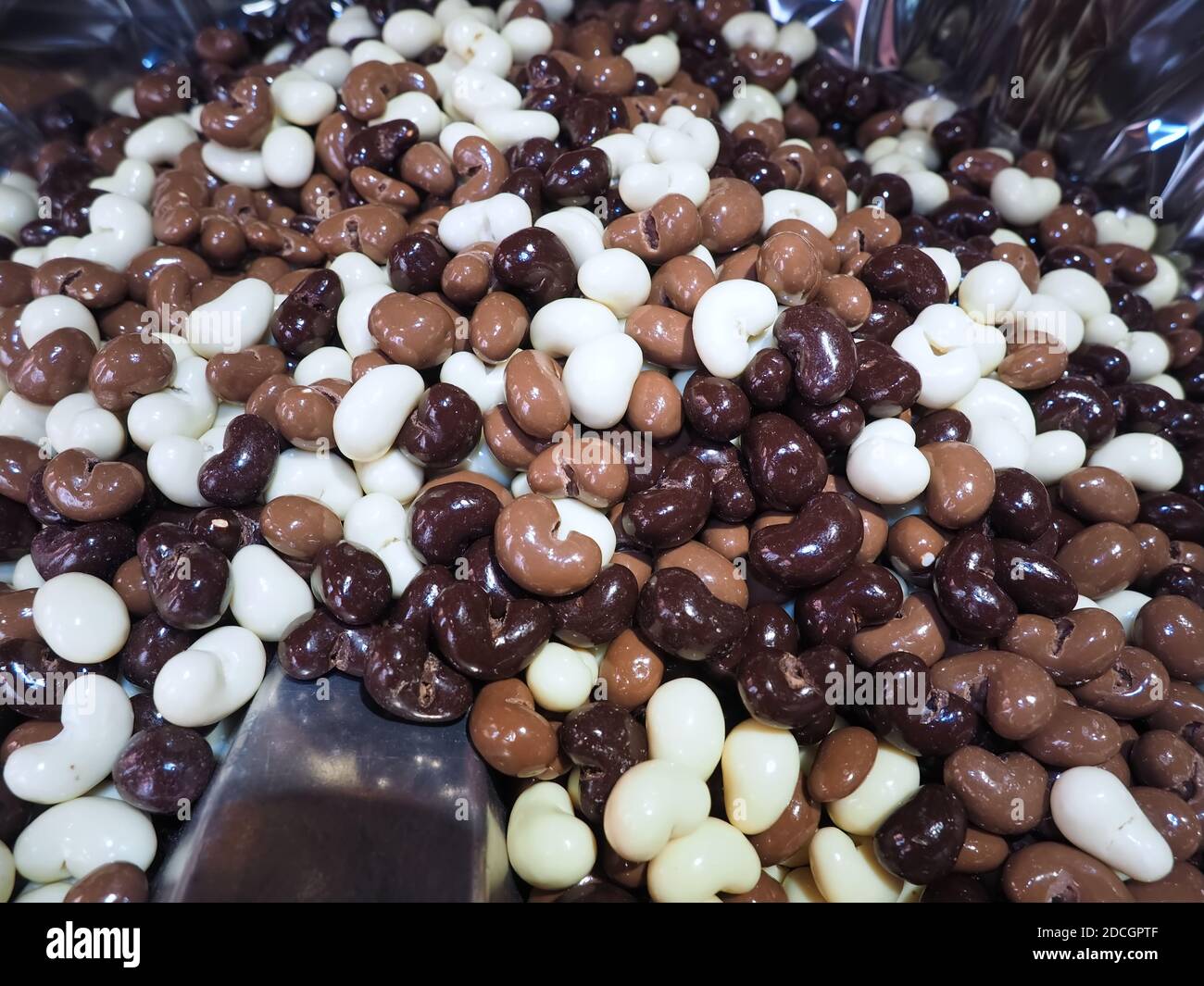 Stapel von Schokolade überzogen Nüsse mit braunen, dunklen und weißen Schokolade Stockfoto