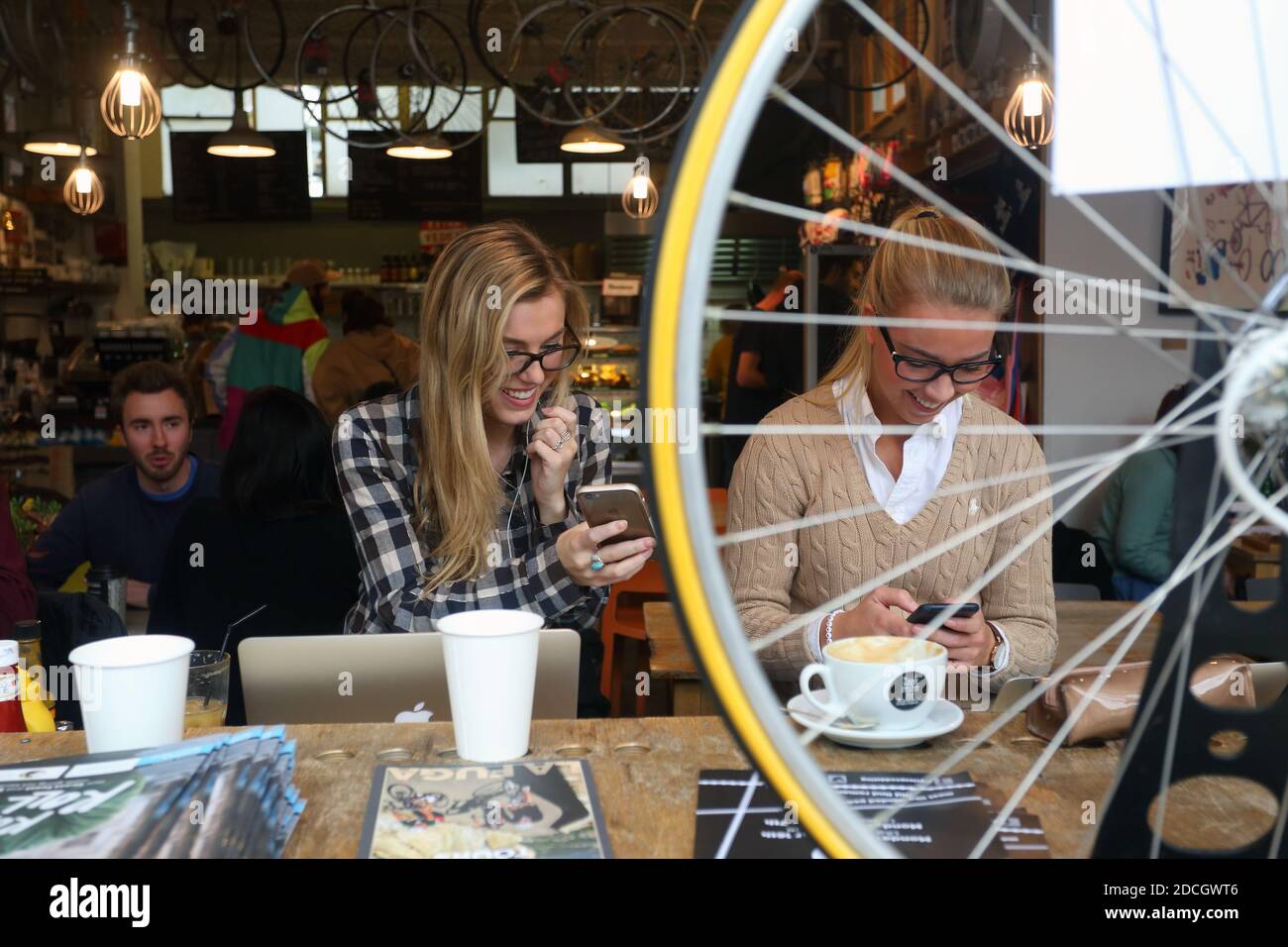 Zwei kaukasische junge Freundinnen, die Spaß haben und Erinnerungen mit einem Smartphone genießen, während sie Kaffee im Londoner Café genießen. Stockfoto
