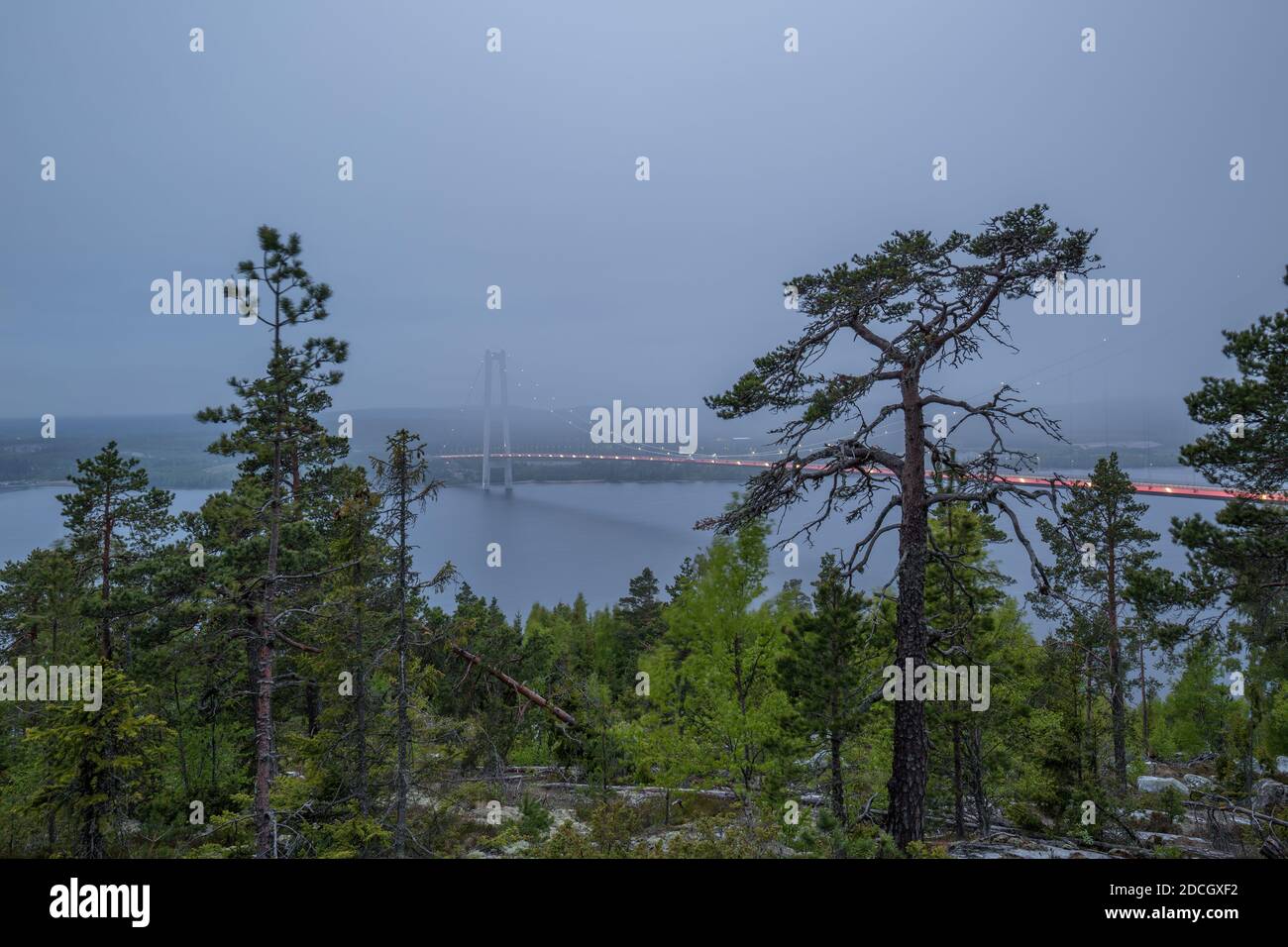 Höga Kustenbron, die Hochküstenbrücke, die den Fluss Ångermanälven bei Veda, Schweden überquert, verschwindet an einem späten Abend fast in der niedrigen Wolkendecke. Stockfoto