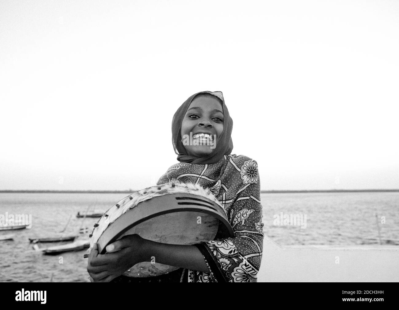 Porträt eines lächelnden suaheli-Mädchens, das Trommel spielt, Lamu County, Lamu, Kenia Stockfoto
