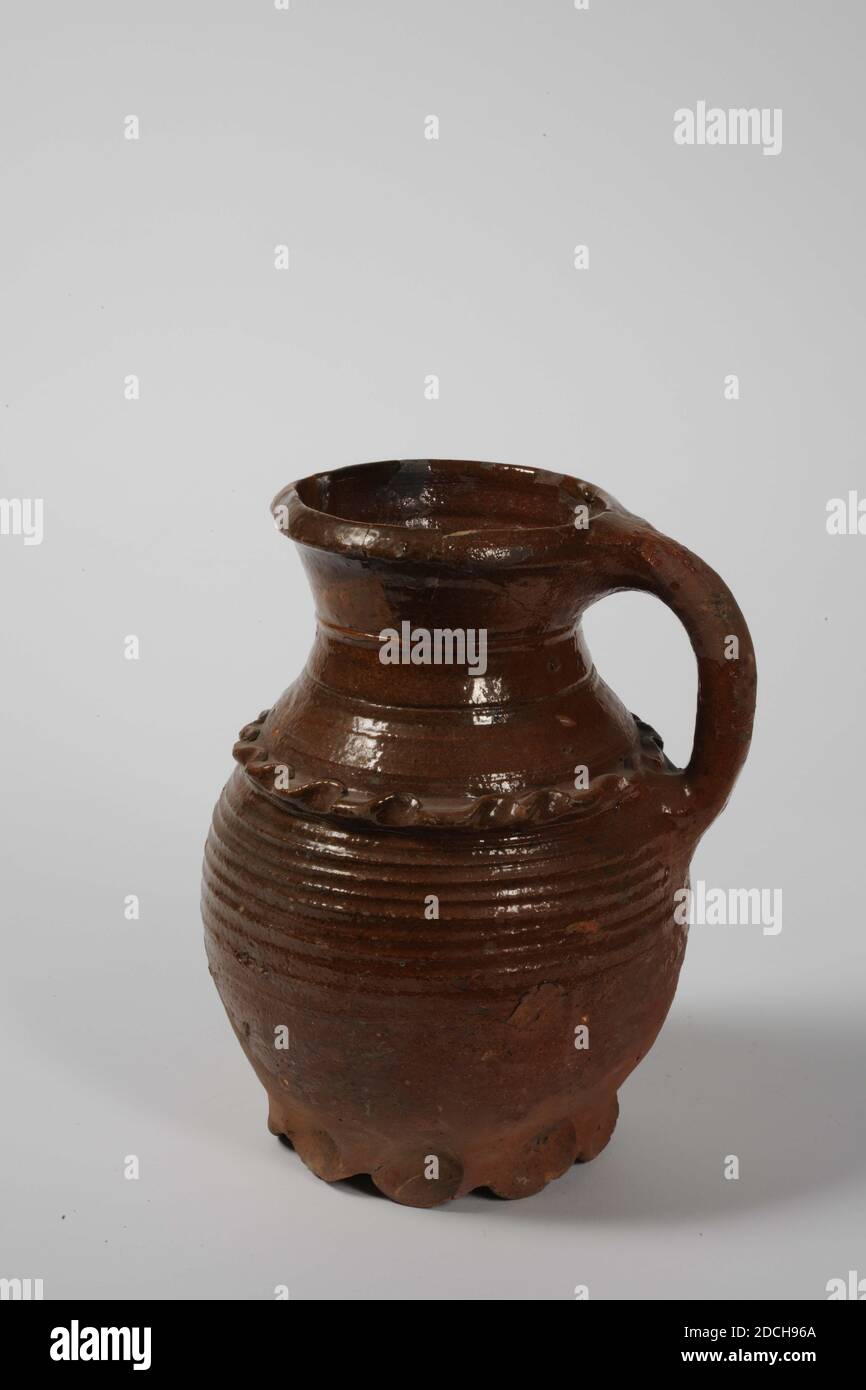 Jug, Anonymous, ca. 1300, Bleiglasur, Steingut, allgemein: 22 x 17.5 x 16cm 220 x 175 x 160mm, Krug mit Griff aus rot gebranntem Steingut mit Bleiglasur. Es hat neun gelappte Beine, einen eiförmigen Körper, einen verengten Hals und einen trichterförmigen Hals. Der Körper hat grob rotierende Ringe und ein gezackter Band auf der Schulter in Relief. Unten ein Etikett: Rodenburch Leiden, 1972 Stockfoto