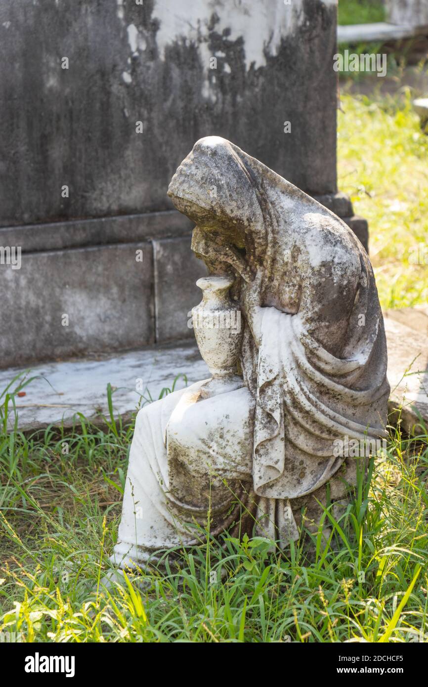 Alte verwitterte Steinskulptur einer sitzenden Trauerfigur mit einer Vase auf einem Friedhof. lafayette Friedhof New Orleans Louisiana Stockfoto