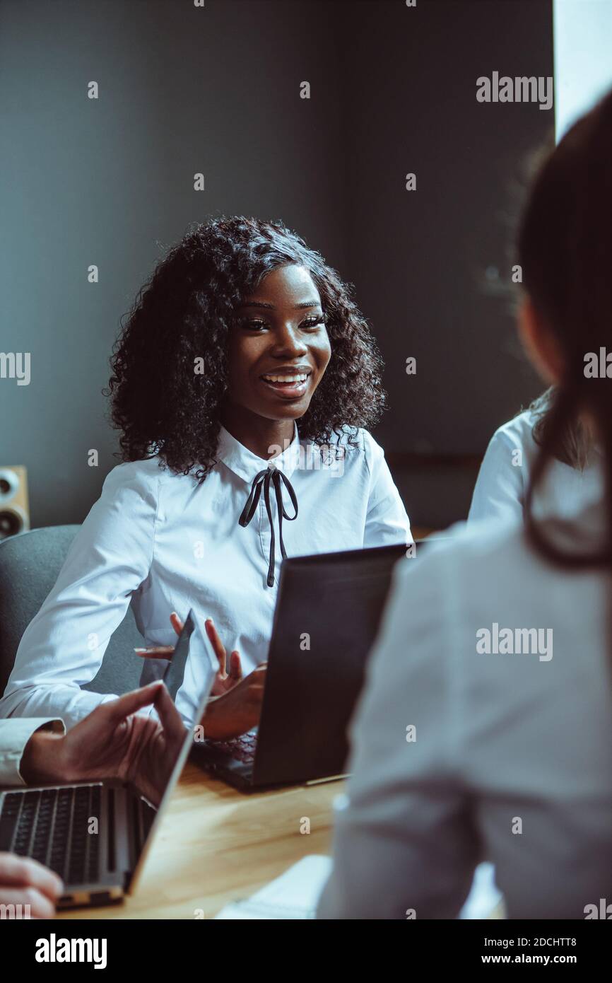 Das ehrgeizige afro-amerikanische Mädchen diskutiert finanzielle Pläne für das Unternehmen. Team von jungen verschiedenen Geschäftsleuten, die am Desktop-Computer in zusammenarbeiten Stockfoto
